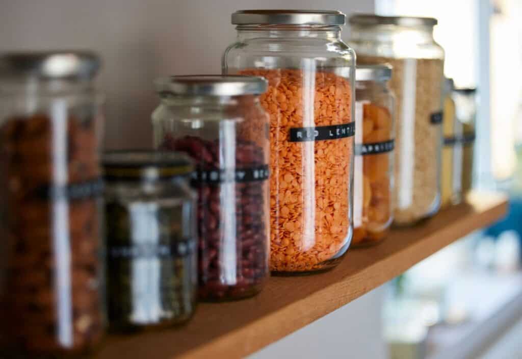 A shelf full of glass jars filled with food.