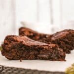 Two chocolate brownies on a piece of paper with a blurred background.