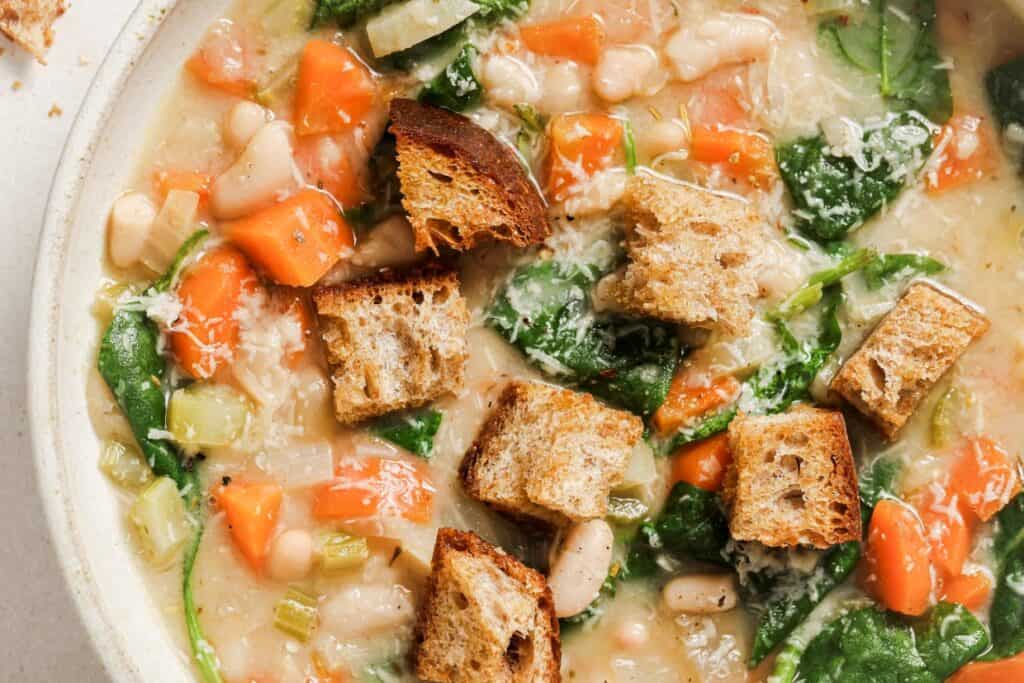 Bowl of vegetable soup with croutons and spinach.