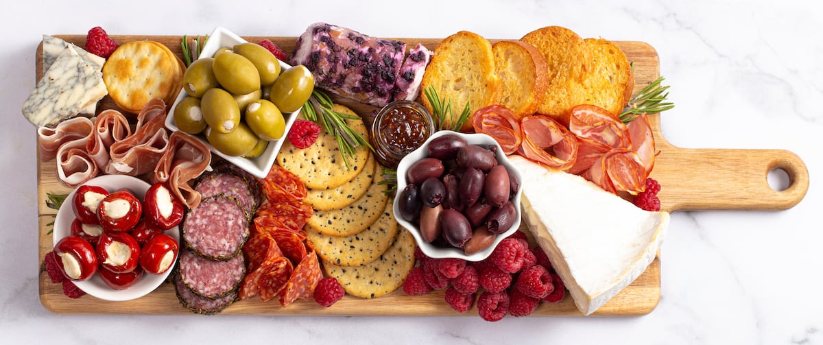 A charcuterie board featuring an assortment of cheeses, meats, olives, crackers, and fruits.
