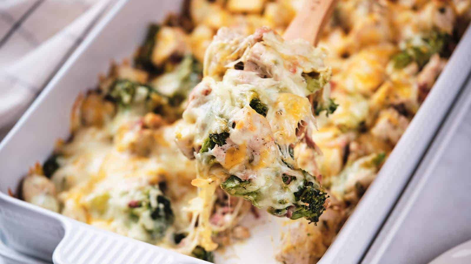 Fork lifting a cheesy bite from a plate of baked chicken and broccoli casserole.