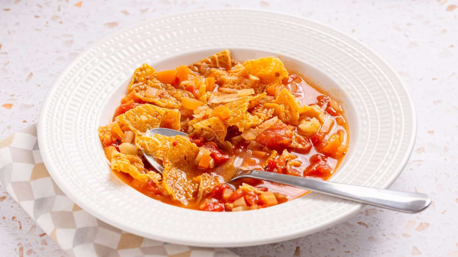 A bowl of hearty tomato-based soup with cabbage.