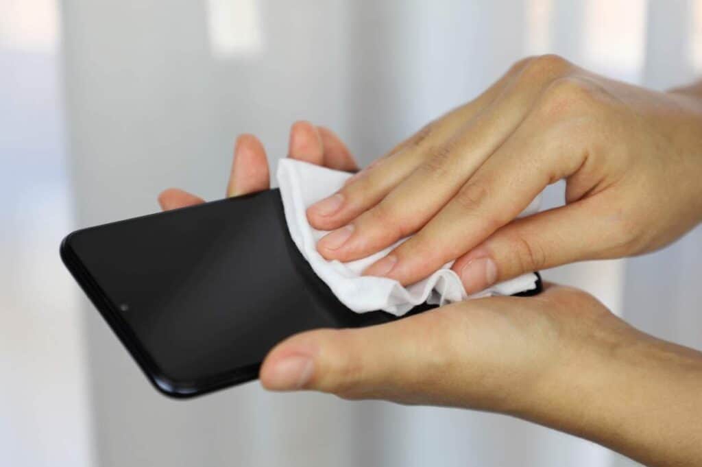 Person cleaning a smartphone screen with an eco-friendly cloth.