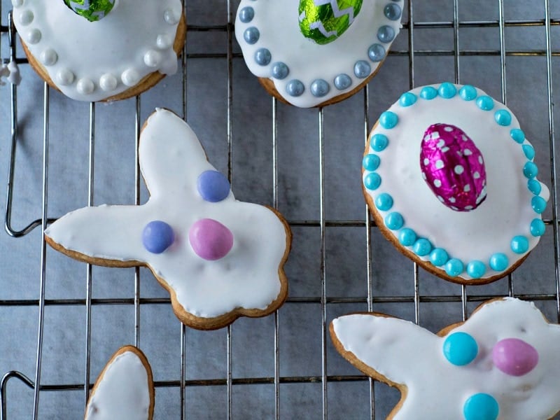 Assorted iced easter cookies in egg and bunny shapes on a wire rack.