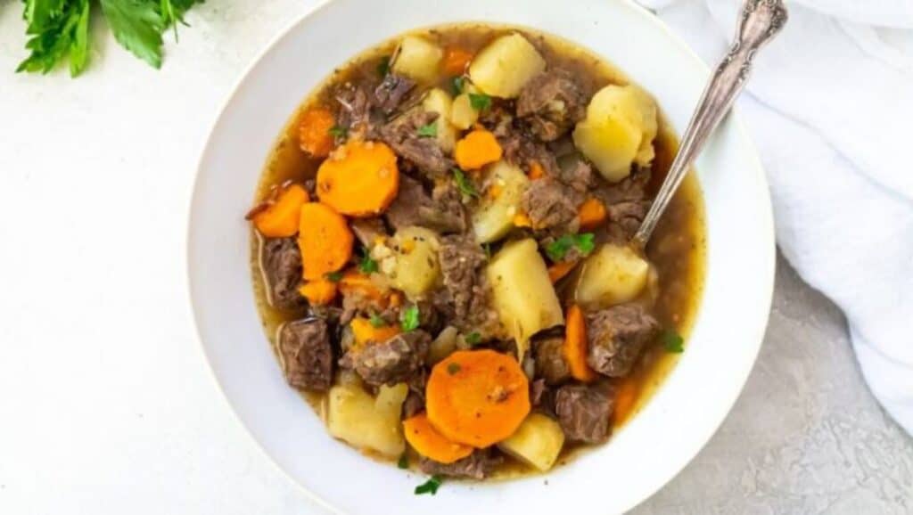 A bowl of beef stew with carrots and potatoes.