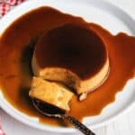 Caramel pudding served on a white plate with caramel sauce drizzled over it.