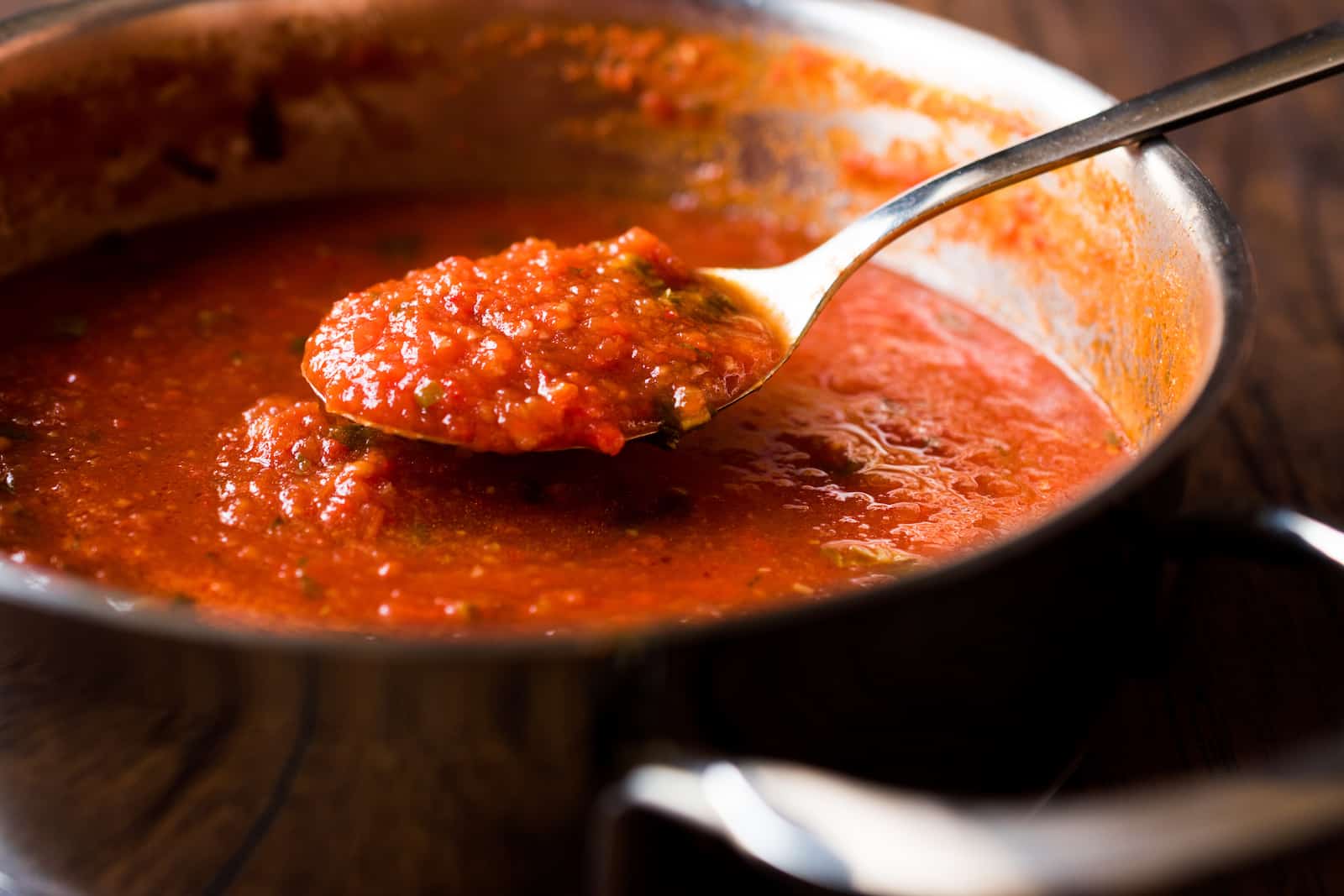 A pot of tomato sauce with a spoon in it.