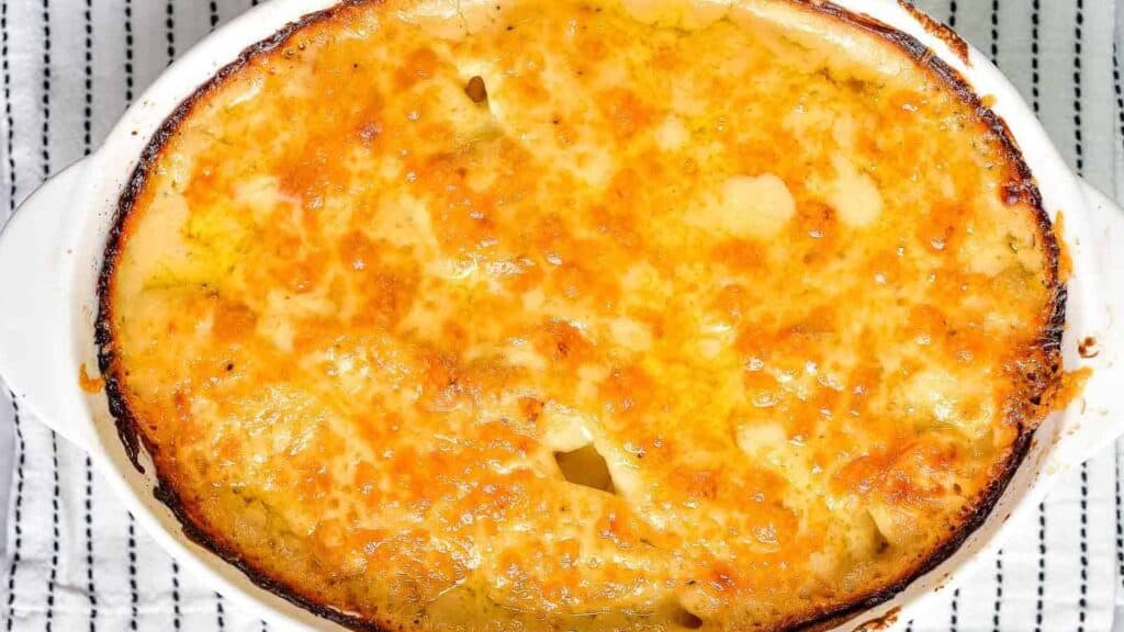 Baked macaroni and cheese in a white casserole dish with a golden-brown crust.