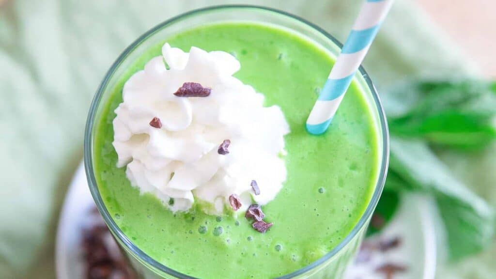 A green smoothie with whipped cream and chocolate chips.