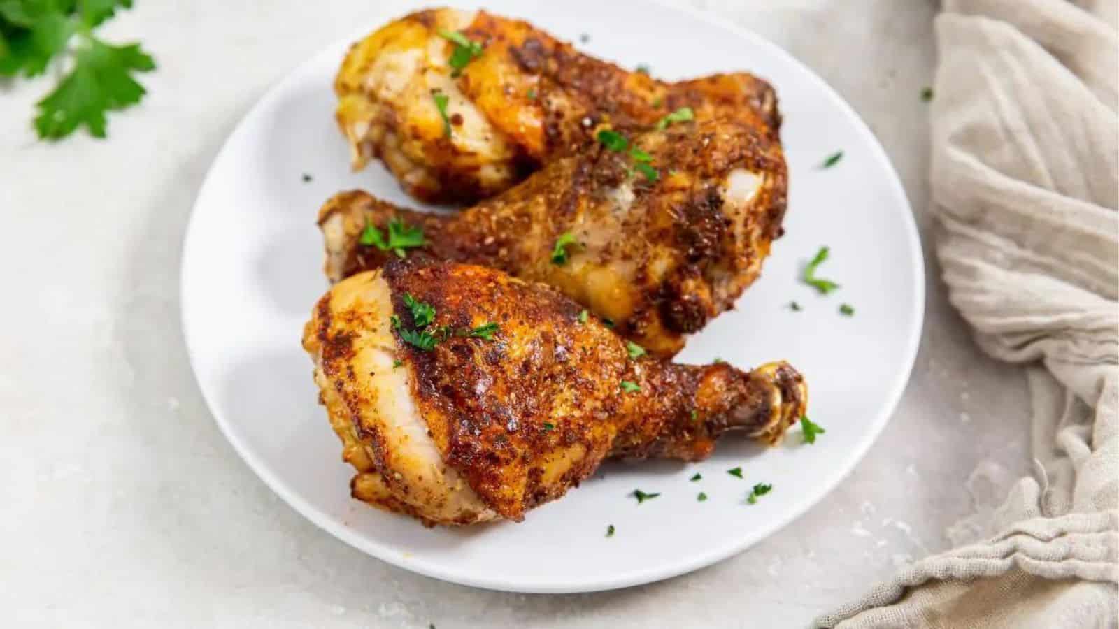 Air Fryer Blackened Chicken Legs on a white plate with parsley.