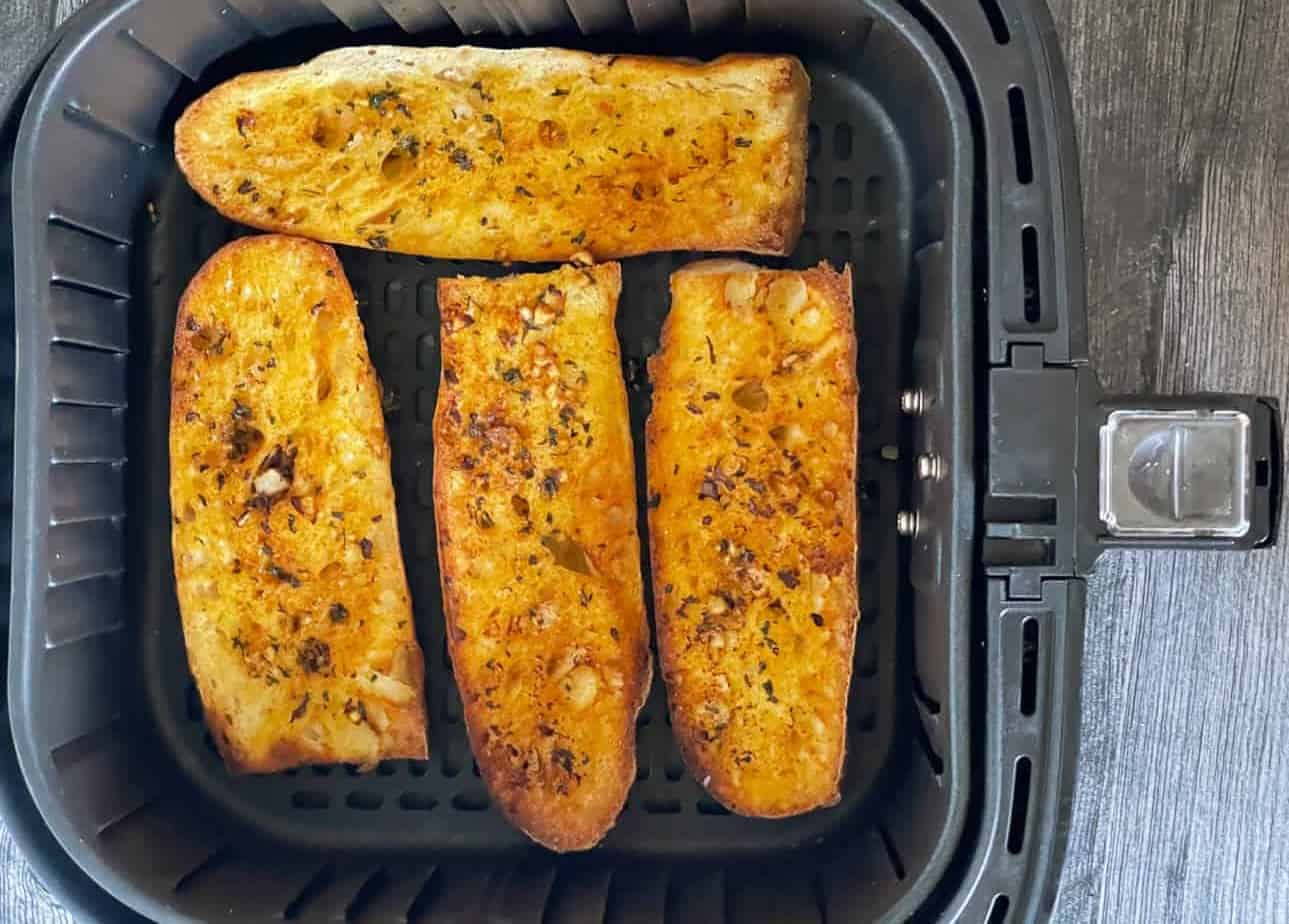 Pieces of garlic bread in an air fryer basket.