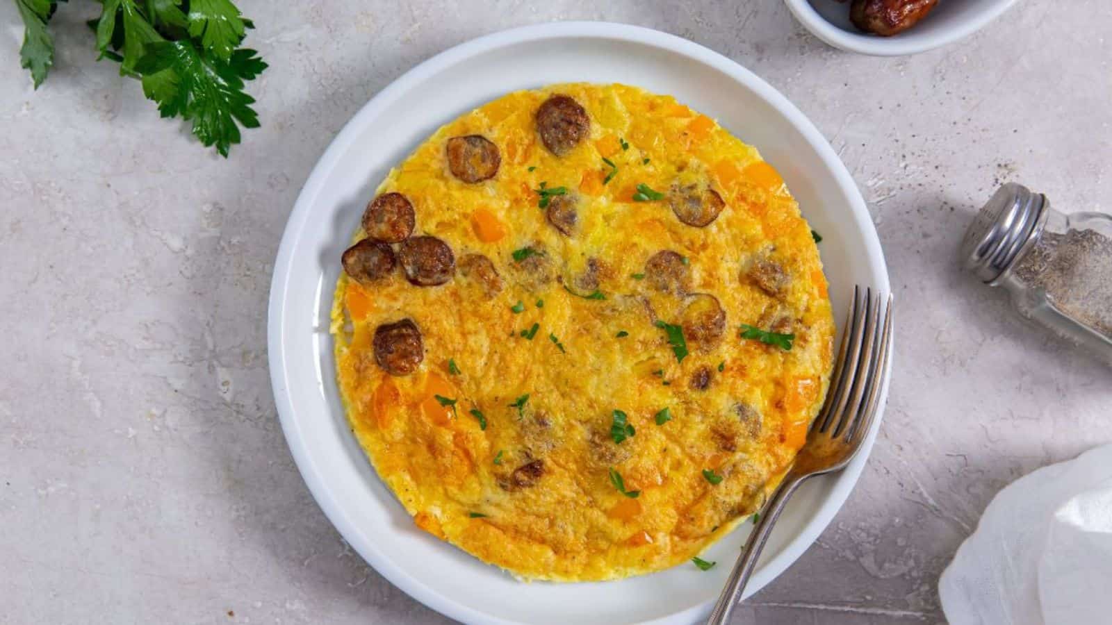 Air Fryer Omelette with bell peppers, parsley, cheese, and sausage on a white plate with a fork.
