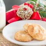 A bottle of milk and freshly baked cookies on a table adorned with holiday decorations.