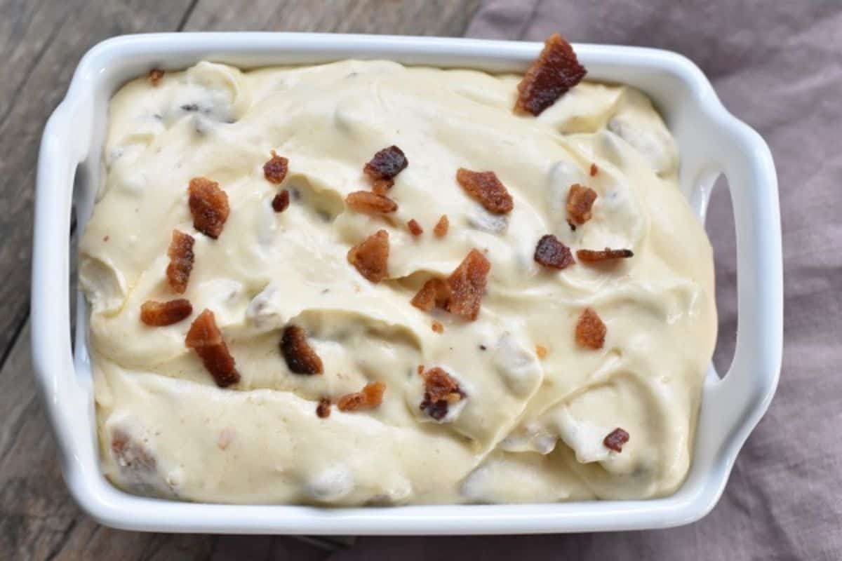 A white dish with cheese and bacon in it.
