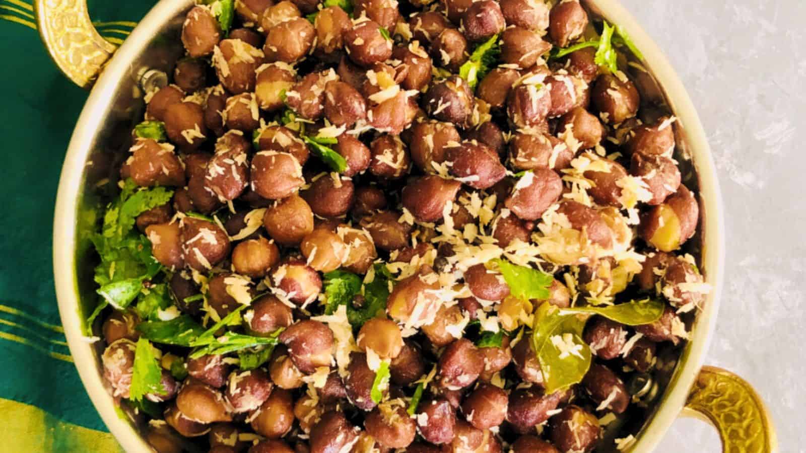 A bowl of Kadlekalu Usli salad garnished with coconut and cilantro, served on a green tablecloth.