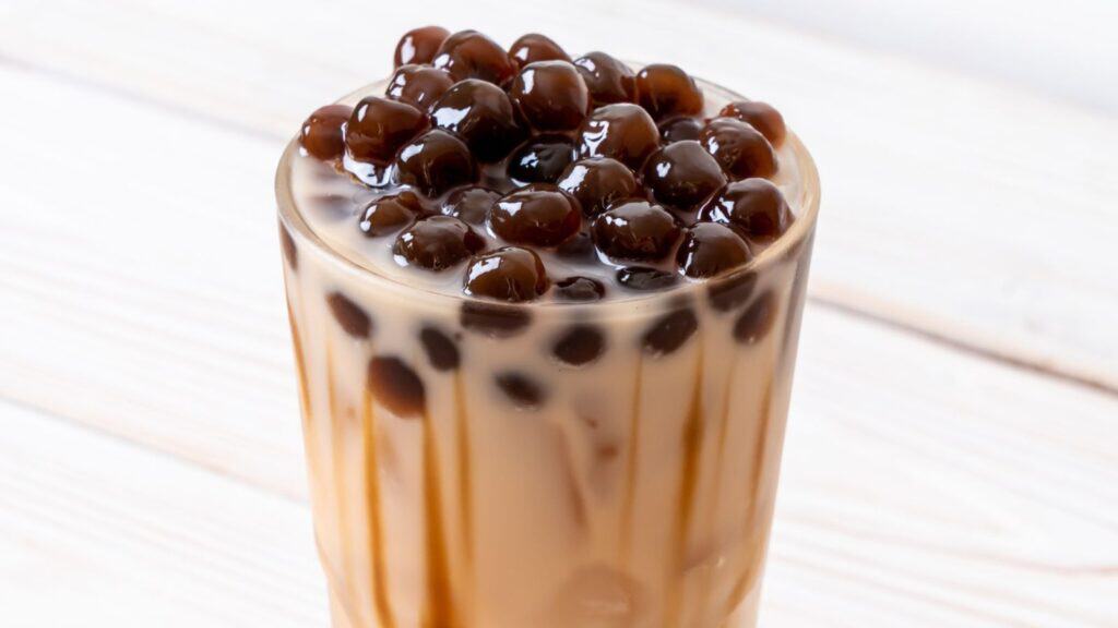 A glass of bubble tea with a layer of tapioca pearls on top and tea mixed with milk underneath, offering sweet sips without the guilt.