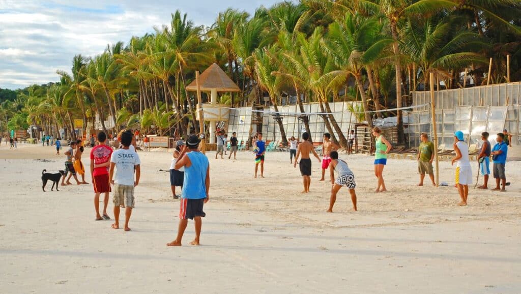 People enjoying a casual game of beach volleyball at must-visit places in the Philippines.