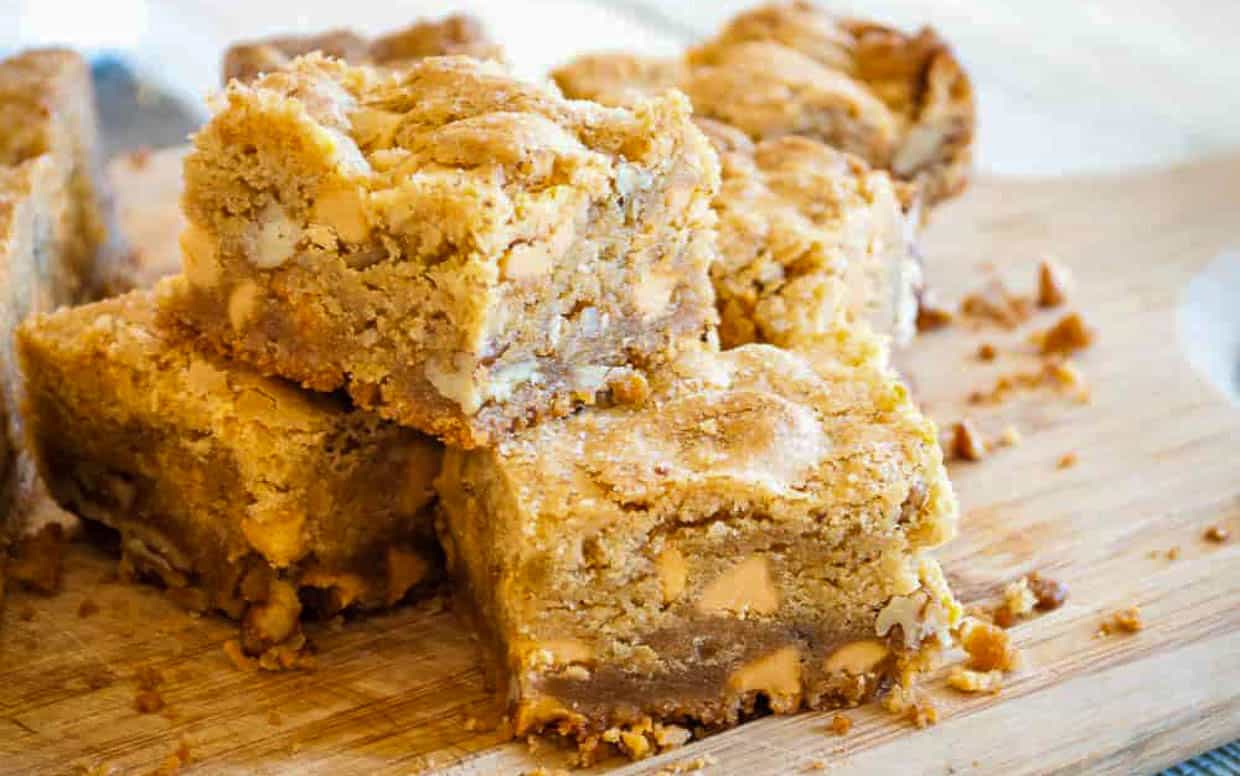 A stack of blondie bars on a wooden cutting board.