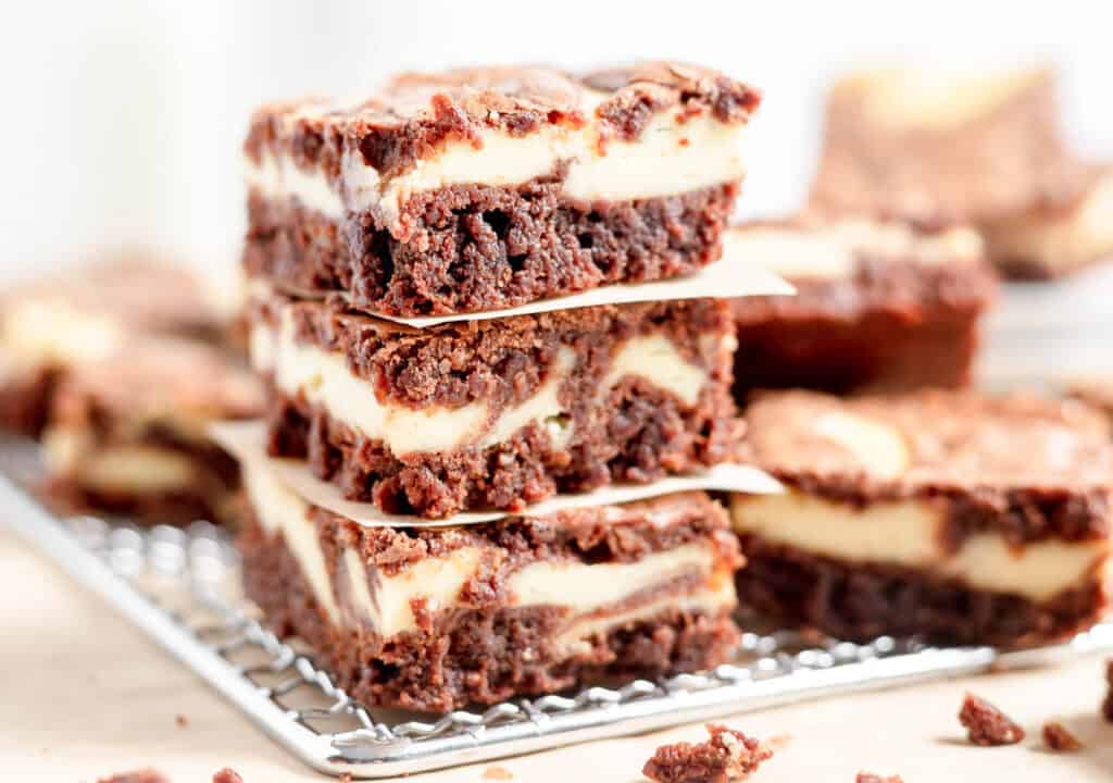 Stack of marbled cheesecake brownies on a cooling rack.