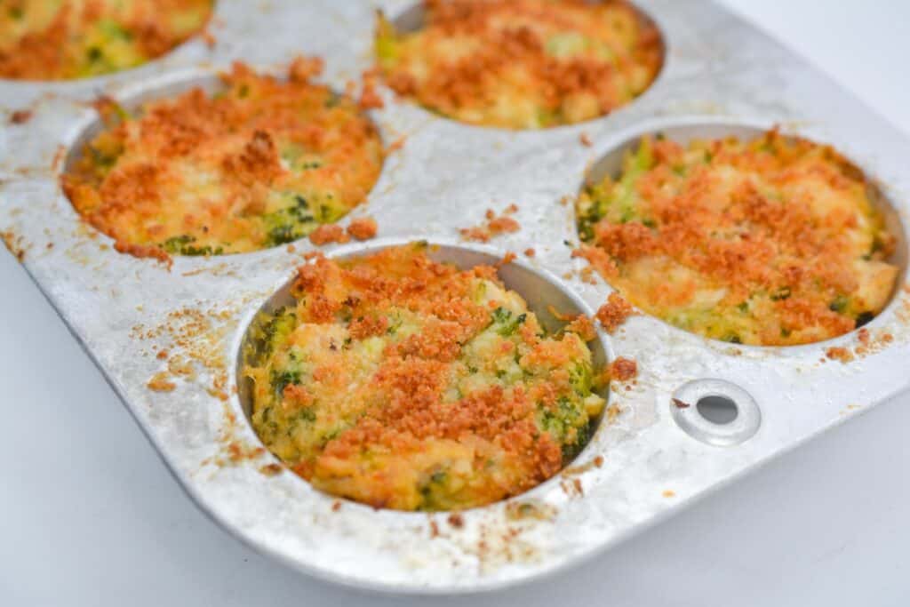 Freshly baked muffins in a muffin tin, with a golden-brown crust visible on top.