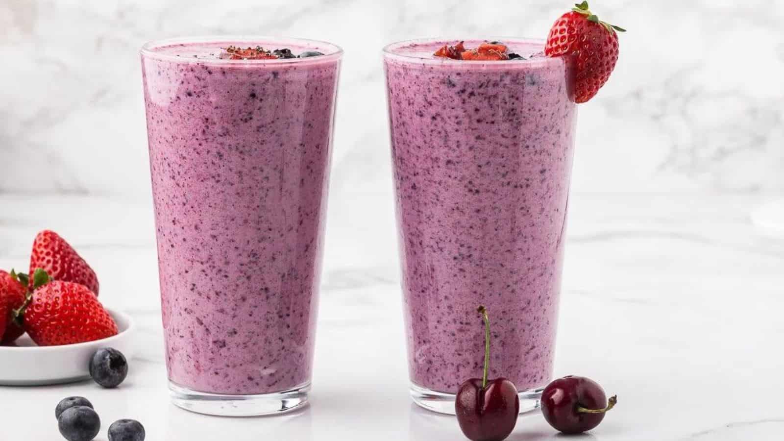 Two tall glasses filled with berry smoothie with chia seeds.