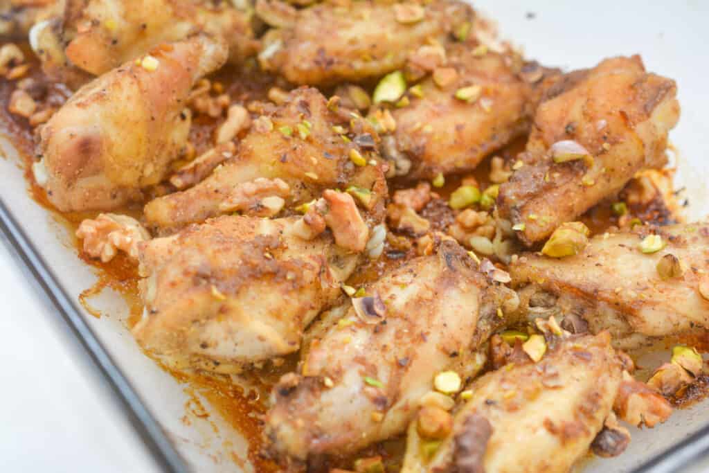 Oven-baked chicken wings seasoned and garnished with chopped nuts.