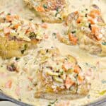 Chicken dinners: thighs in a creamy sauce with diced vegetables in a skillet.