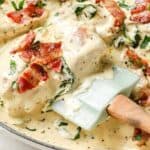 Creamy chicken dish garnished with bacon and herbs in a skillet.