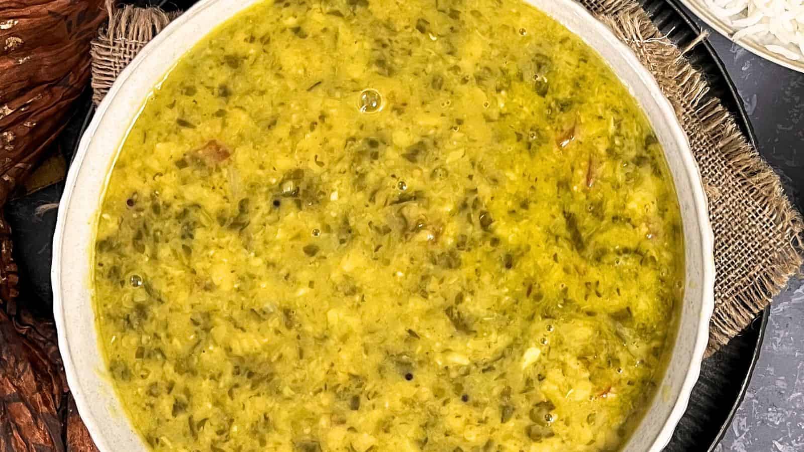 A bowl of Dal Palak, spiced and cooked to a thick consistency, served on a woven mat.