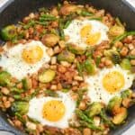 A skillet containing a meal with brussels sprouts, eggs, and diced potatoes.