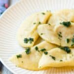 A plate of stuffed pasta, possibly ravioli or pierogi, garnished with herbs.