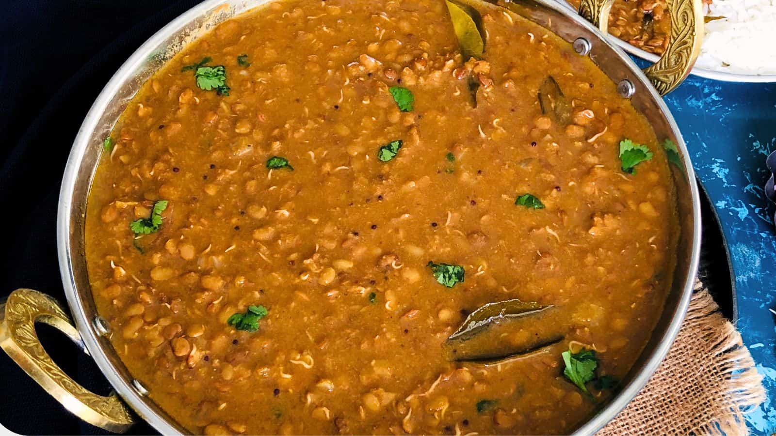 Hurali Saaru in a pot garnished with cilantro, featuring a rich, spiced lentil stew.