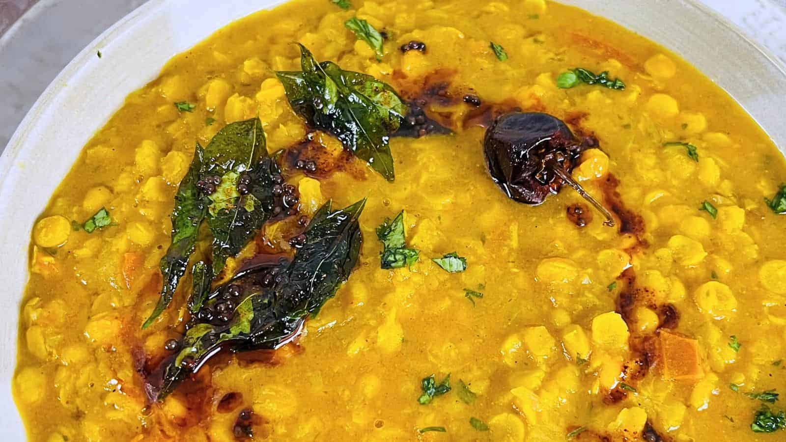 Chana Dal with yellow lentils, garnished with fresh cilantro and tempered spices, including curry leaves and dried chilies.