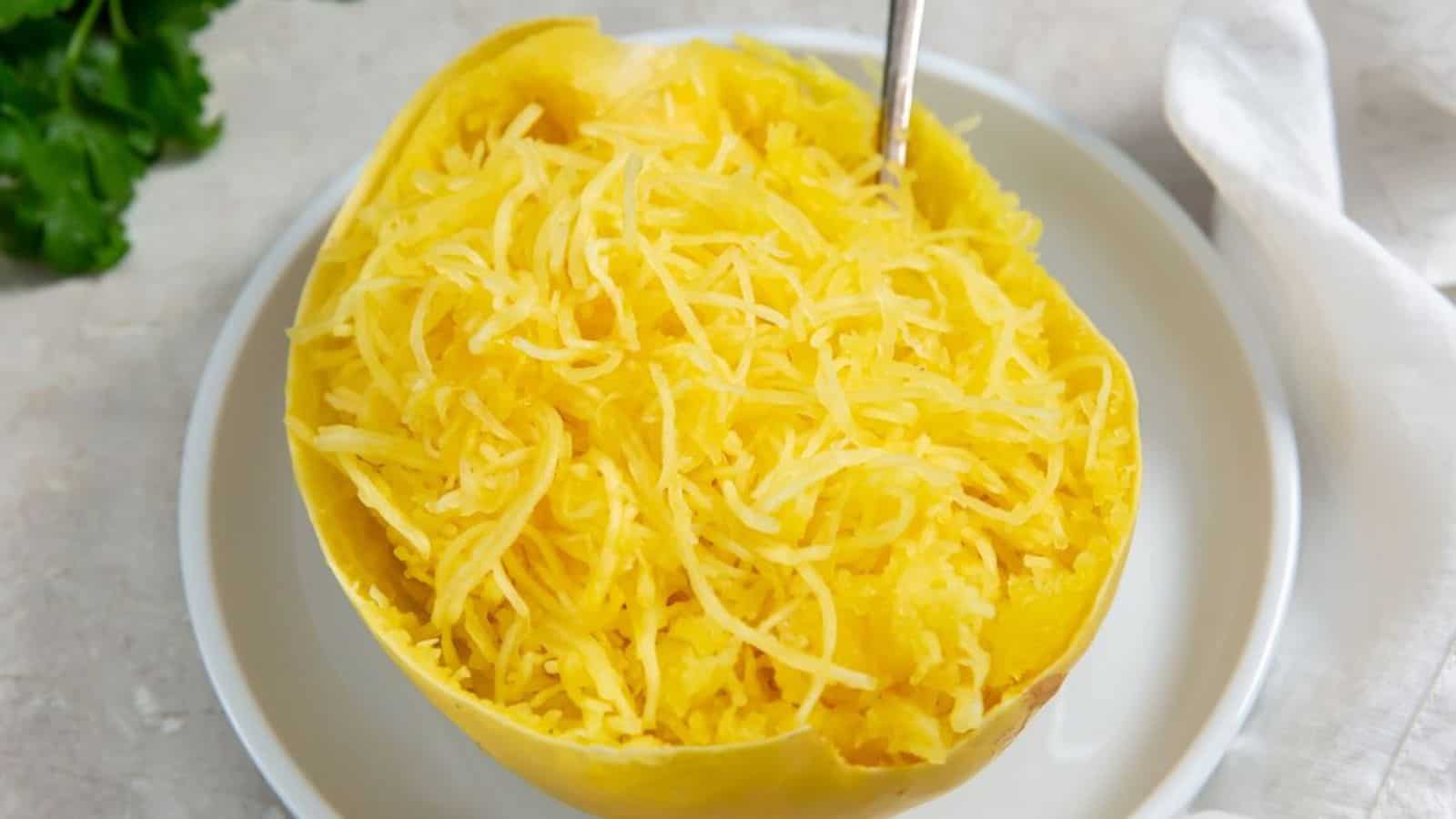 Instant Pot Whole Spaghetti Squash with parsley, salt, and pepper on a white plate and a fork.