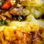 A close-up of a shepherd's pie with a golden mashed potato topping over a savory meat and vegetable filling.