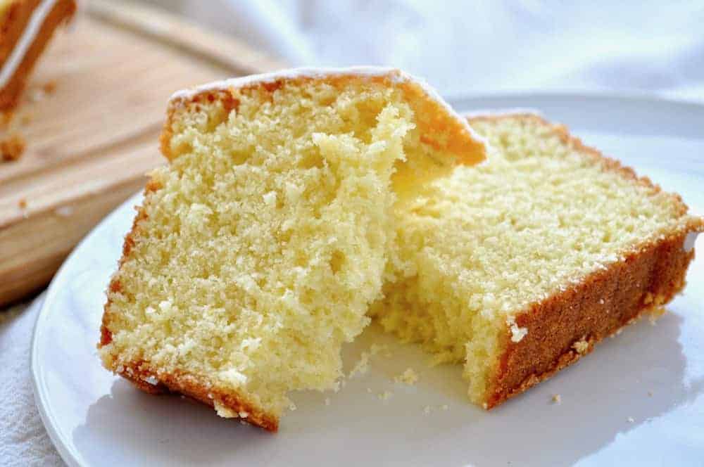 Sliced pound cake on a white plate, showcasing its moist crumb texture.