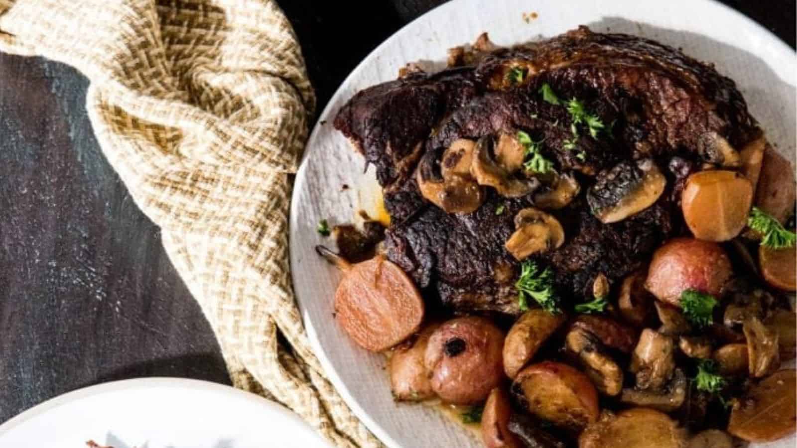 Low Carb Instant Pot Pot Roast with potatoes. mushrooms, and parsley on a white plate.