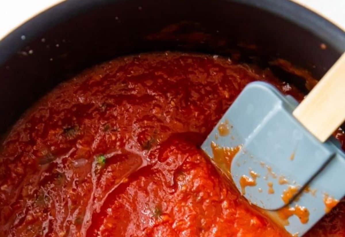 Low Carb Spaghetti Sauce in a black pot with basil and a spatula.