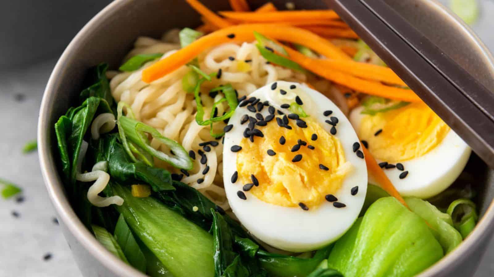 A bowl of ramen with soft-boiled egg, vegetables, and sesame seeds.