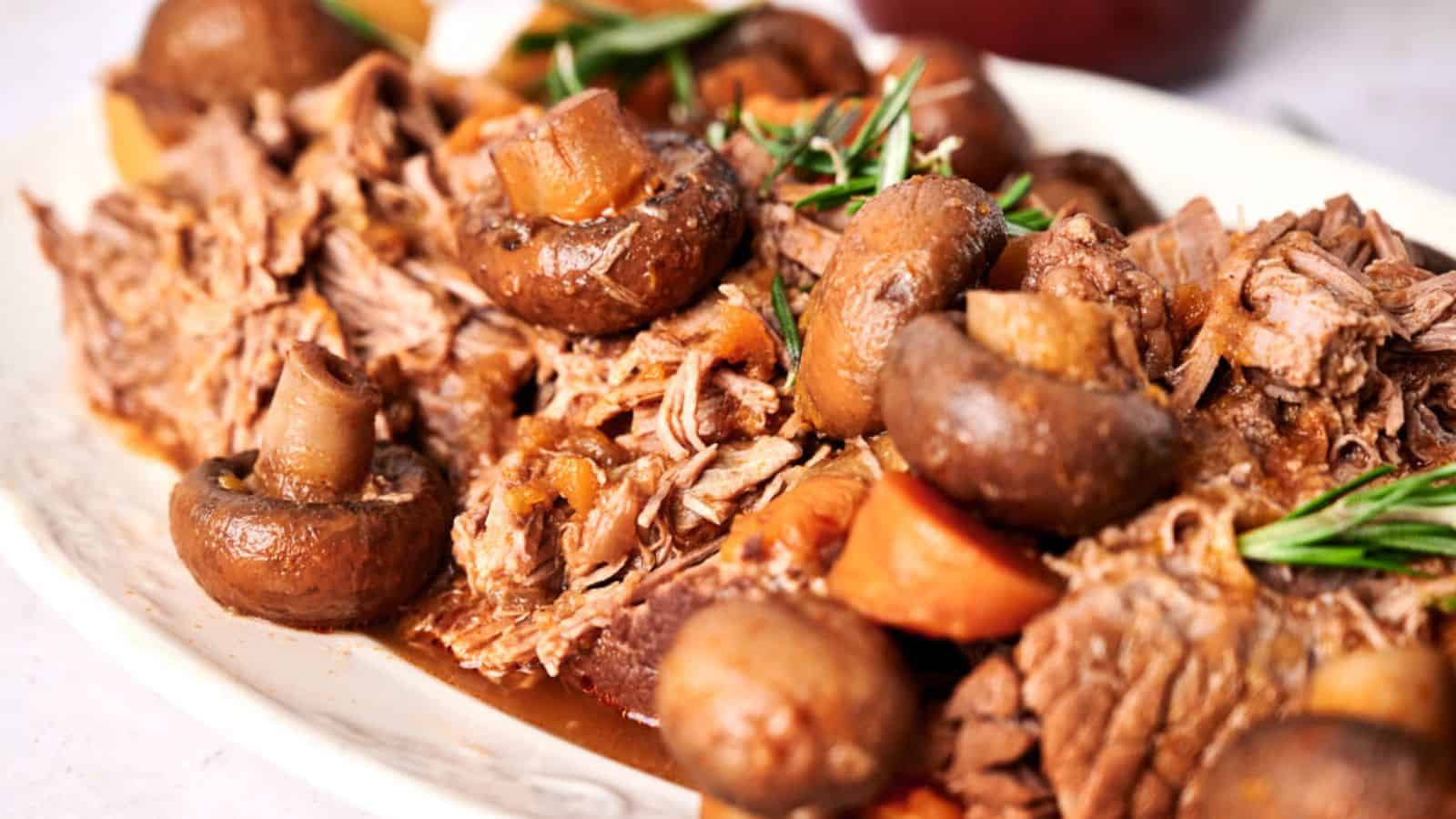 Slow cooker pot roast with mushrooms and carrots garnished with fresh rosemary.