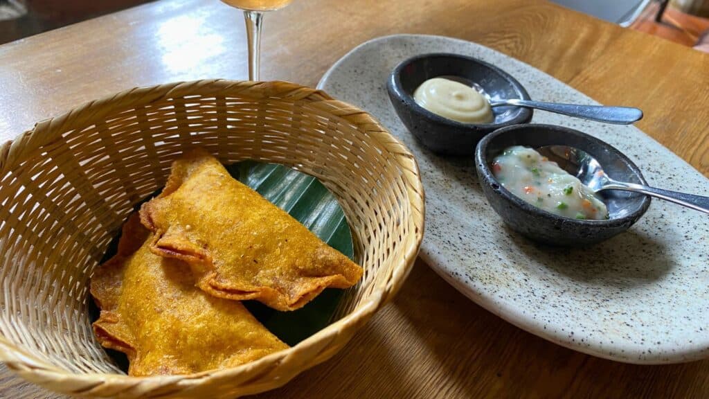 A basket of fried empanadas served with two types of dipping sauce.