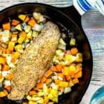 An easy weeknight meal featuring a grilled pork chop with diced carrots and potatoes in a cast iron skillet on a wooden table.