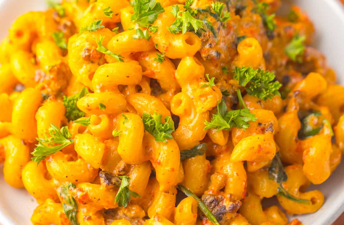 A close-up of creamy macaroni and cheese garnished with parsley.