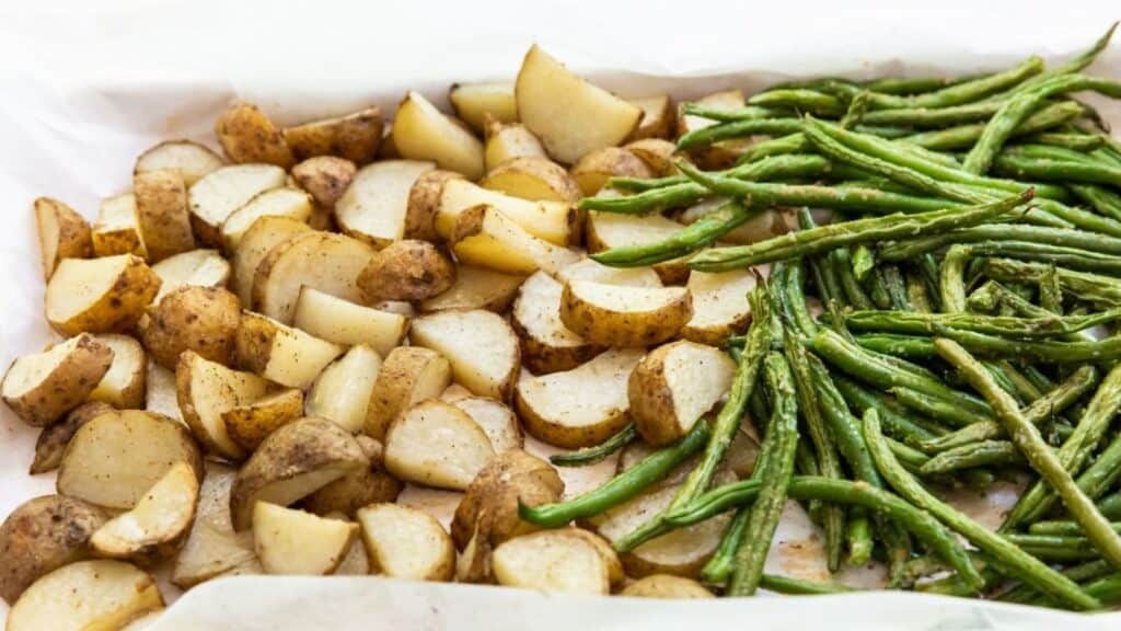 Roasted potato and green beans spread on a baking sheet.