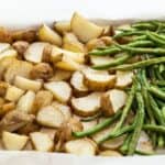 Roasted potato and green beans spread on a baking sheet.