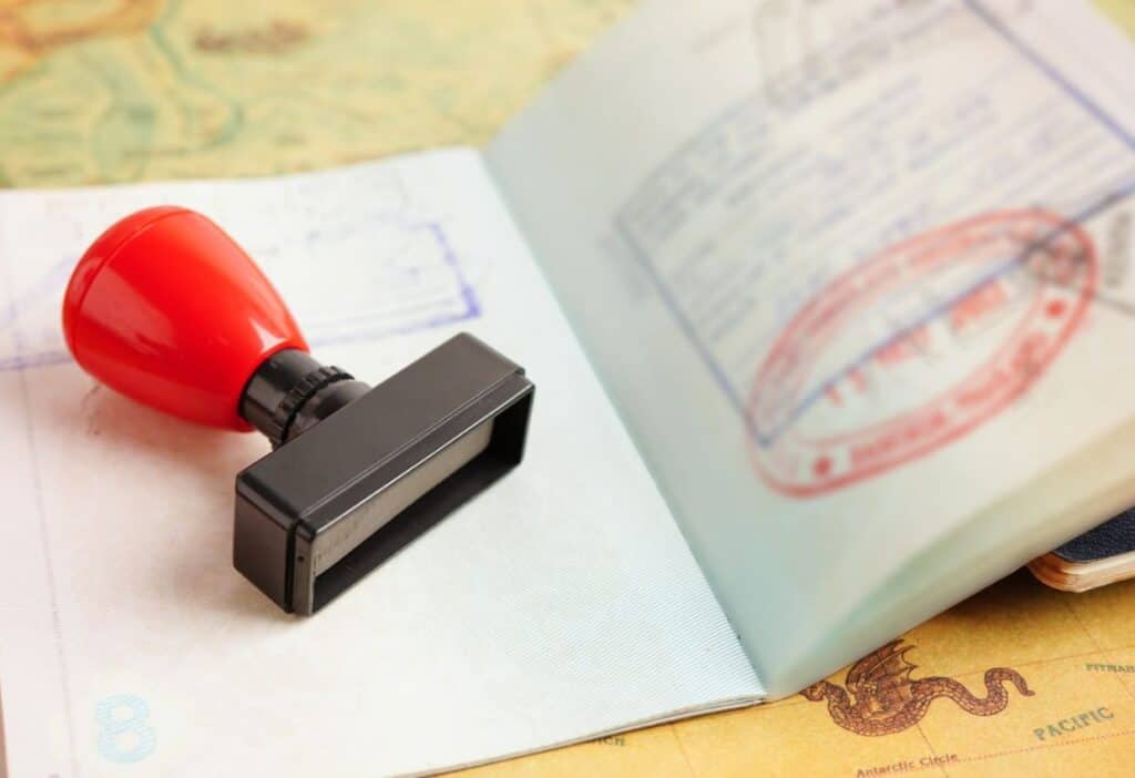 A passport with entry stamps and a rubber stamp lying on a map, symbolizing international travel.