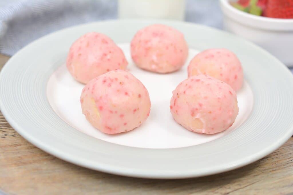 A plate with six strawberry-flavored dough balls for breakfast recipes.