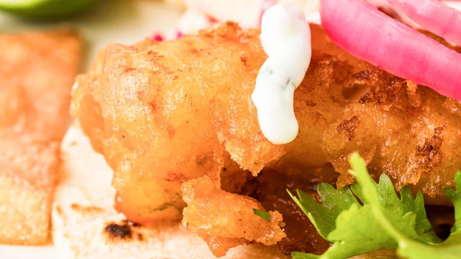 A closeup of beer-battered fish inside a fish taco.