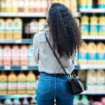 Woman with curly hair shopping for groceries in a supermarket aisle.
