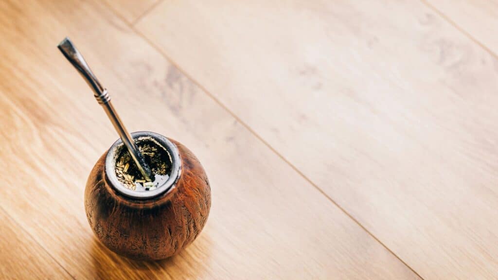 Traditional yerba mate in a wooden gourd with a metal straw on a wooden table, offering sweet sips without the guilt.